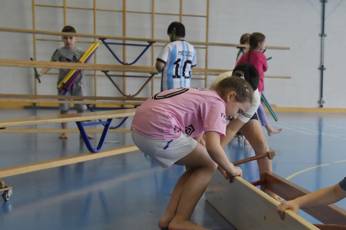 Fünf Kinder bauen Geräte in einer Turnhalle auf.