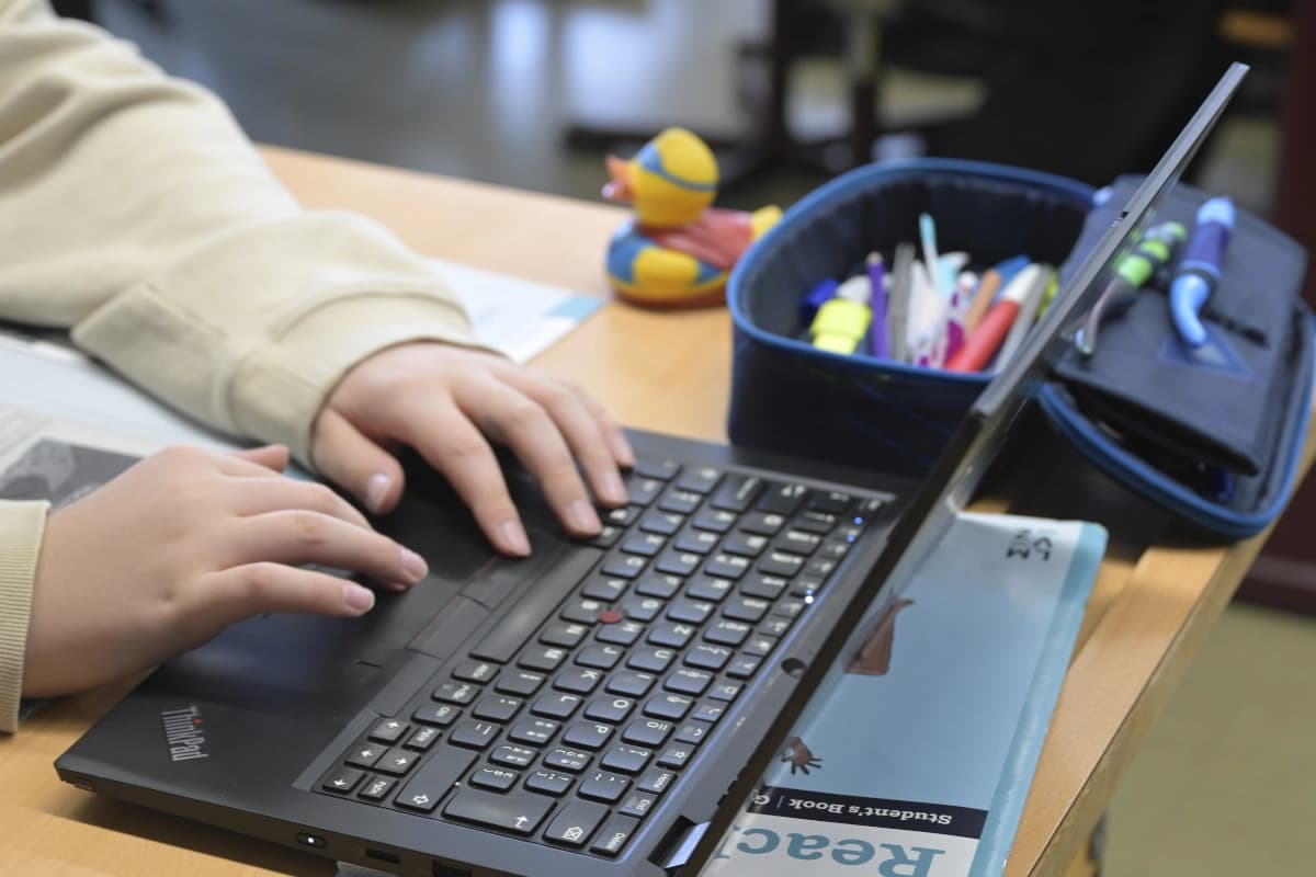 Ein offener Laptop, man sieht die Hände eines Jugendlichen auf der Tastatur.