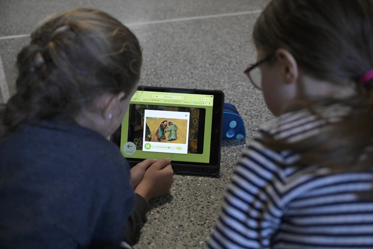 Zwei Kinder beugen sich über ein Tablet, sie sind nur von hinten zu sehen.