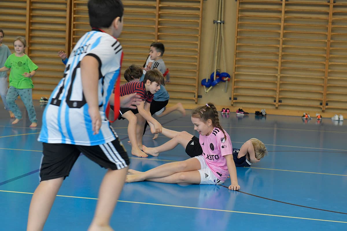 Kinder rennen durch die Turnhalle und rollen auf dem Boden.