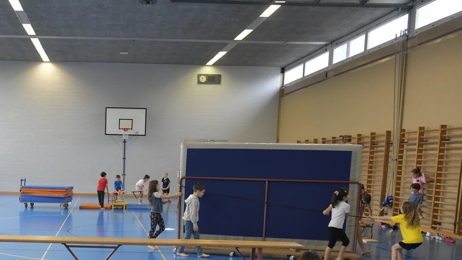 Einblick in eine Turnhalle, Kinder transportieren Matten.