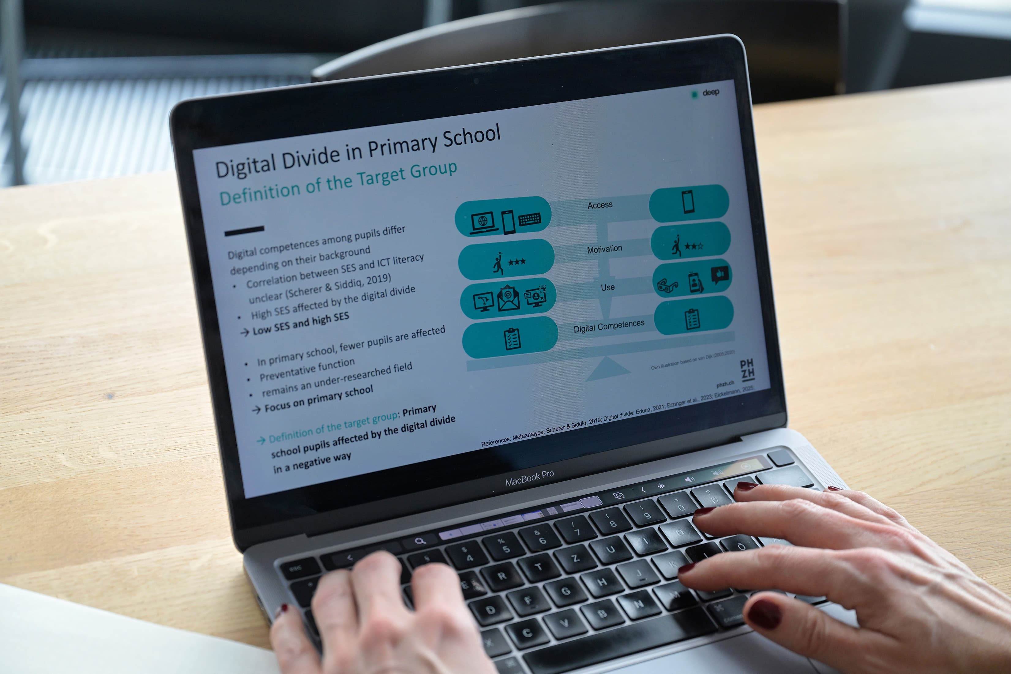 Ein Mac Book Pro, zwei Frauenhände an Tastatur und auf dem Screen ist eine Studie zu sehen mit dem Titel "Digtal Divide in Primary School".