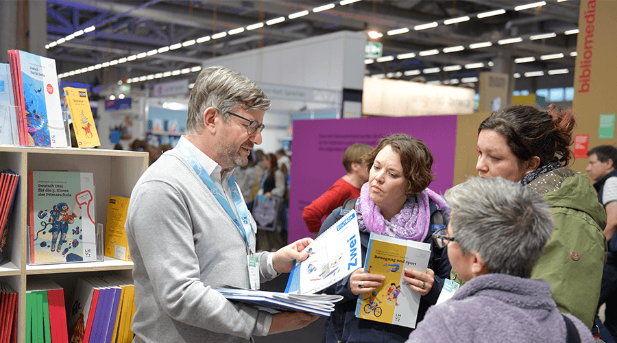 LMVZ-Mitarbeiter berät Lehrerinnen an einer Messe.